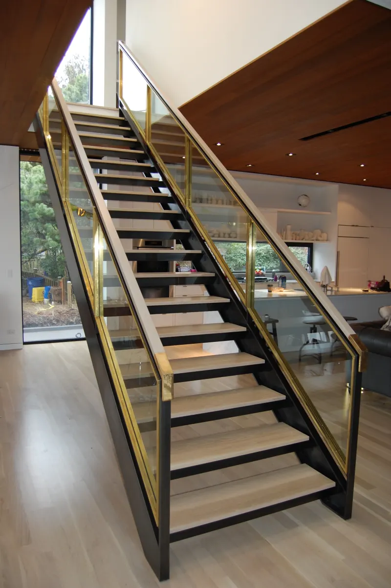 Open-riser steel staircase with glass panels and stainless steel railing details