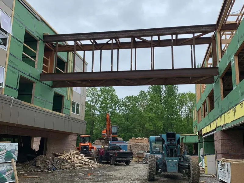 Steel pedestrian bridge spanning between two buildings during construction