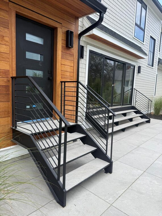 Floating exterior steel staircase with porcelain treads and horizontal bar railing